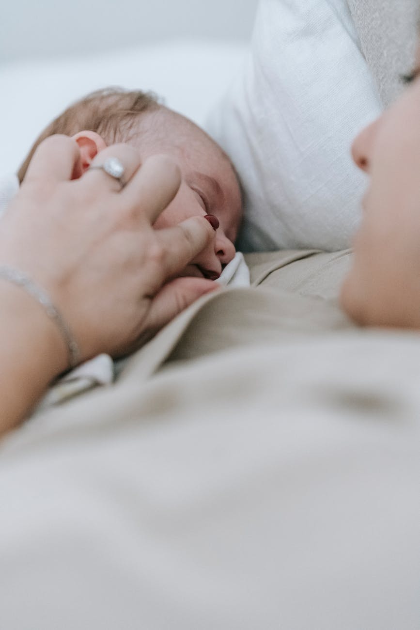 faceless mother with sleeping baby on bed