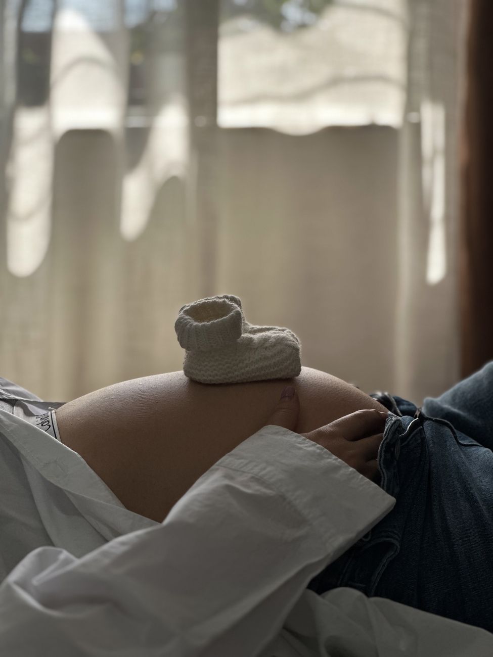 pregnant woman with baby booties on belly indoors