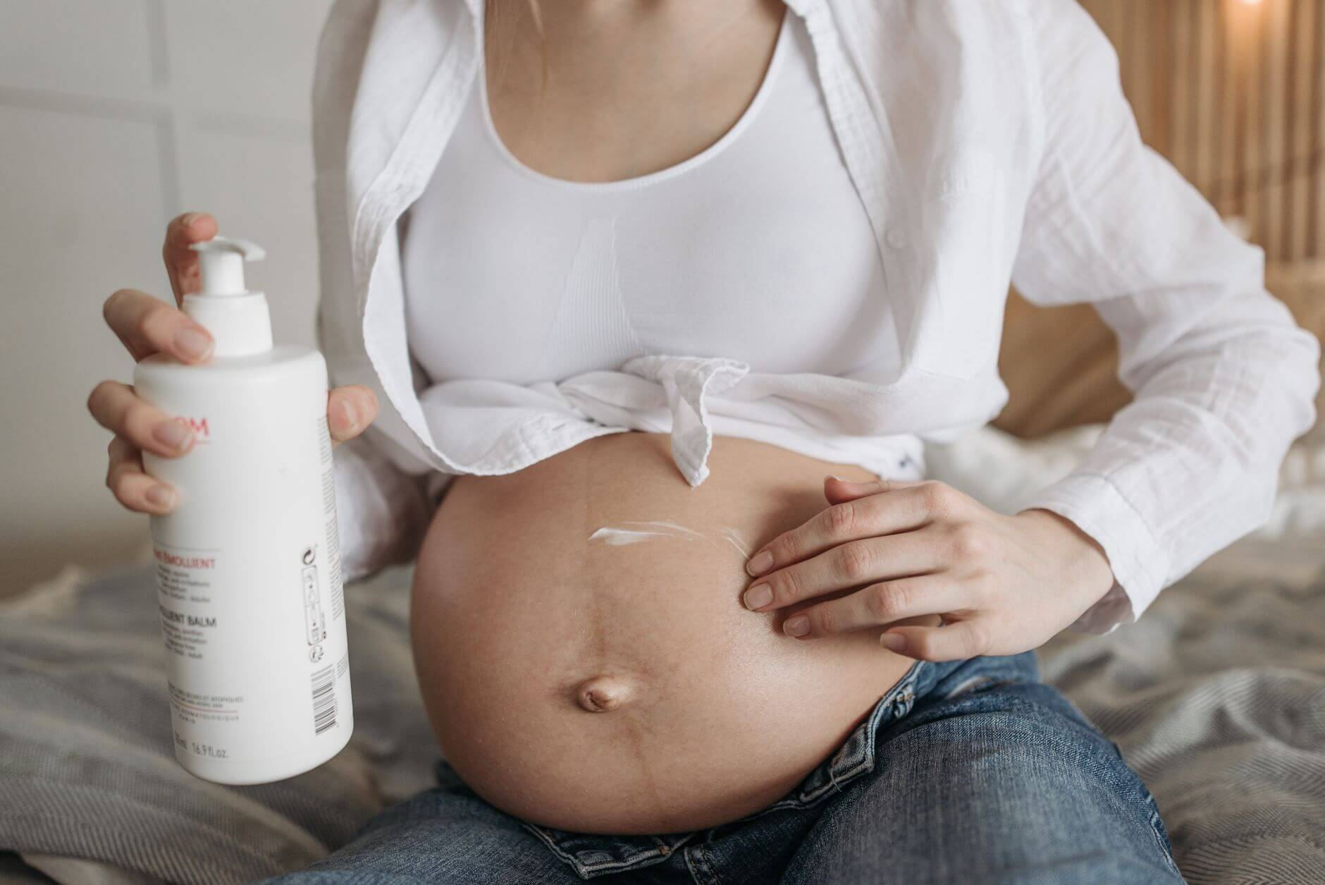 a close up shot of a woman applying a belly balm on her baby bump
